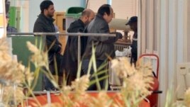 An unidentified person right, is followed by Algerian officials as they enter a morgue in Ain Amenas Algeria Monday, Jan. 21, 2013,  where the bodies of the persons killed during the hostage situation at the gas plant in Ain Amenas,. At least 81 people ha