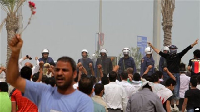 Anti-government protesters chant and wave flowers in front of riot police in Manama, Bahrain, March 13, 2011