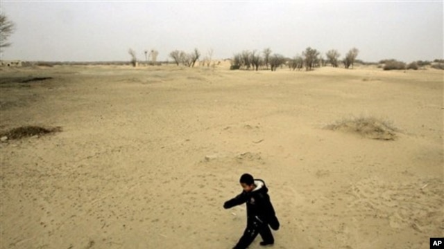 A child walks across a sand dune in Gansu province, China, where desertification threatens for force farmers from their land.
