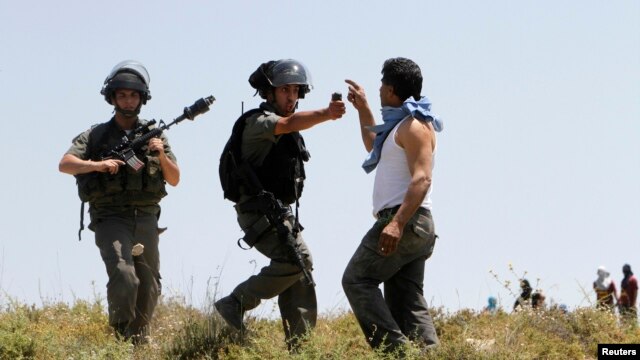 Seorang polisi Israel mengacungkan semprotan merica ke arah seorang warga Palestina untuk membubarkan bentrokan antara pemukim Yahudi dan warga Palestina di desa Urif dekat Nablus, Tepi Barat (30/4).