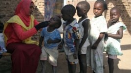 A social worker gives polio drops to children from al-Muniera village in Madani, FILE November 18, 2007. 