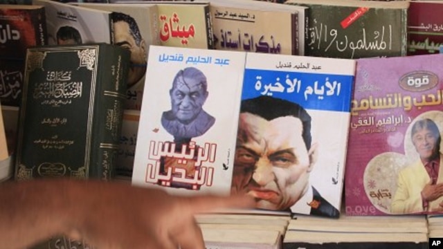 An Egyptian displays books showing cartoons on the covers of former Egyptian President Hosni Mubarak in Cairo, Egypt, May 23, 2011