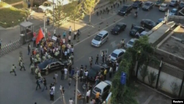 Security officers surround a car carrying U.S. ambassador Gary Locke after anti-Japan demonstrators tried to block the car outside the U.S. embassy in Beijing, September 18, 2012.