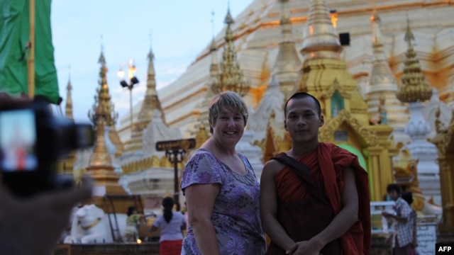 A western tourist poses for a photograph with a Buddhist monk at the Shwedagon Pagoda in Rangoon, Burma, May 31, 2012.