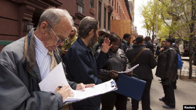 Un hombre revisa su hoja de vida, mientras espera en línea junto a otras personas que buscan trabajo en Nueva York.