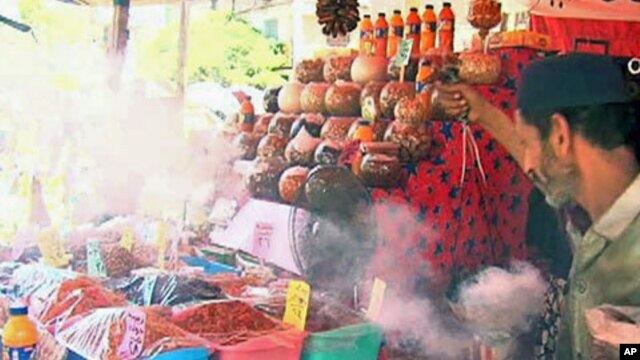 A man spreads incense smoke over the goods to ward off the evil eye, in the marketplace in Cairo, July 2011