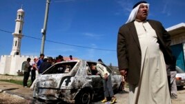 A Palestinian stands near a burnt car in the West Bank village of Kusra, near Nablus, February 21, 2013.