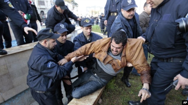 Algerian policemen detain a protester during a demonstration in Algiers, February 12, 2011