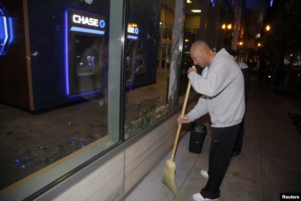 A man sweeps up broken glass after a riot swept through the area in protest to the election of Republican Donald Trump as President of the United States in Portland, Oregon, U.S., Nov. 10, 2016.