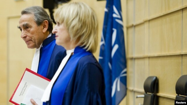 Presiding Judge Bruno Cotte from France (L) and Judge Christine Van Den Wyngaert from Belgium (R) stand during the verdict of the trial of Congolese warlord Mathieu Ngudjolo Chui at the International Criminal Court (ICC) in The Hague, December 18, 2012.