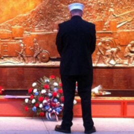 An honor guard pay his respect at the bronze firefighter memorial at the World Trade Center site in New York, September 11, 2011