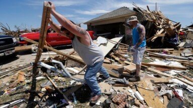 Chad Allcox, left, helps his friend Kevin McElvany, right, the home owner, clear debris away from his destroyed home from Monday's tornado, Moore, Oklahoma, May 22, 2013. 
