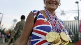 Una aficionada británica camina por el Olympic Park de Londres llevando colgadas medallas de chocolate antes de la Ceremonia de Clausura.