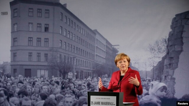 German Chancellor Angela Merkel speaks in front of a photograph showing Bernauer Strasse in November 1989 at the exhibition opening during a ceremony marking the 25th anniversary of the fall of the Berlin Wall at a memorial in Bernauer Strasse in Berlin, 