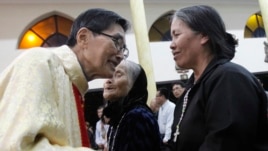 Linh mục Matthew Vũ Khởi Phụng ban phước cho mẹ và chị của ông Ðoàn Văn Vươn.