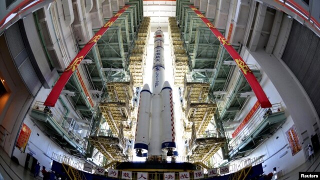 The Shenzhou-9 manned spacecraft, Long March-2F rocket, and escape tower wait to be transferred to the launch pad at the Jiuquan Satellite Launch Center, Gansu province, June 9, 2012.