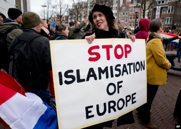 FILE - A woman holds a placard at a rally calling against immigration and what demonstrators see as the Islamization of their communities, in Amsterdam, Netherlands, Feb. 6, 2016.