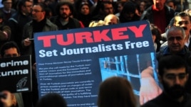 Turkish journalists carry a large sign displaying a letter to Turkish Prime Minister Recep Tayyip Erdogan that calls for the release of jailed journalists, during a demonstration on Istiklal Avenue in Istanbul, on March 13, 2011.