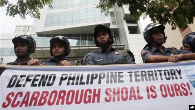 Cảnh sát Philippines đứng sau biểu ngữ của người biểu tình bên ngoài lãnh sự quán Trung Quốc ở khu tài chính của Makati.