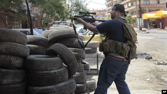 A Sunni gunman fires his weapon during clashes on Syria Street which divided the areas between Sunnis and Alawites, in the northern port city of Tripoli, Lebanon, May 13, 2012. 