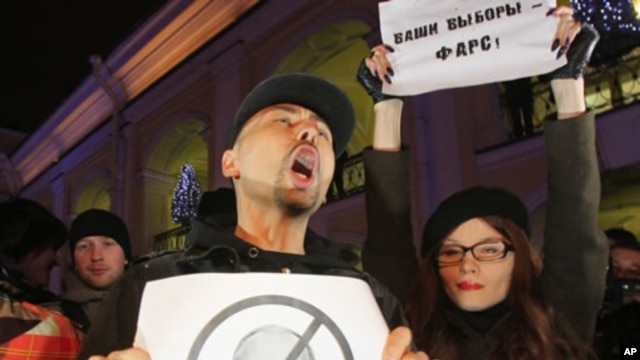 Opposition activists, one of them holding a poster depicting Russian Prime Minister Vladimir and another a poster reading, "Your election is a farce", shout slogans during a protest against vote rigging in St. Petersburg, Russia, December 4, 2011.