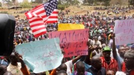 Supporters of Kenya's Opposition party Coalition for Reforms and Democracy (CORD), hold up banners and the US flag ahead of a CORD rally at Uhuru Park, Nairobi, Kenya, Wednesday, Sept. 23, 2015, in solidarity with striking teachers.