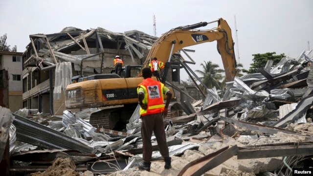 An emergency official watches an excavator dig through the rubble of a collapsed building in the Victoria Island district of Lagos, November 5, 2013. 