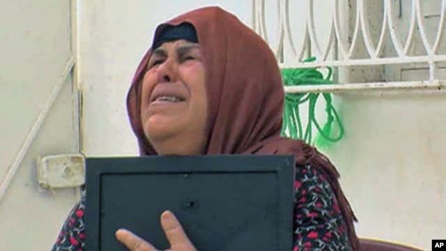 Umm Zine Nceri, the mother of 36-year-old Adel Hammami, who threatened to expose fraud within Tunisia's old ruling RCD party and was brutally killed, cries as she holds a photo of Hammami, in Sidi Bouzid, Tunisia, August 2011