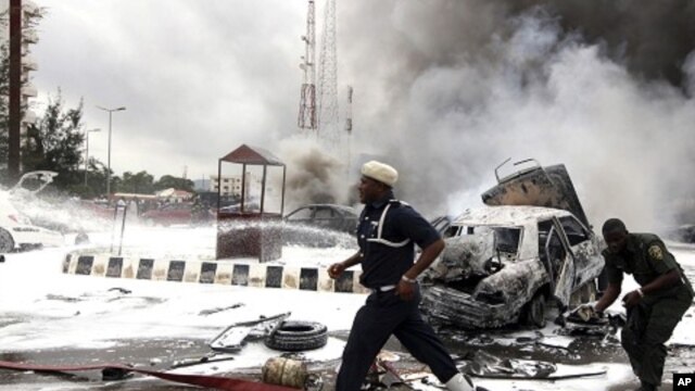 Members of emergency services work at the scene of an explosion at a police station after a suspected suicide bomber was killed and many vehicles were destroyed in Abuja, June 16, 2011