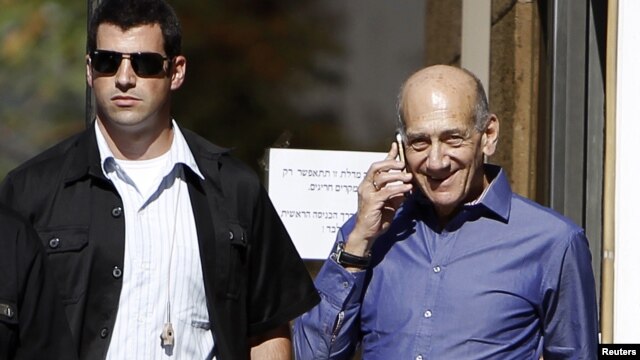 Former Israeli Prime Minister Ehud Olmert (R) speaks on the phone as he leaves the Jerusalem District court, September 24, 2012.