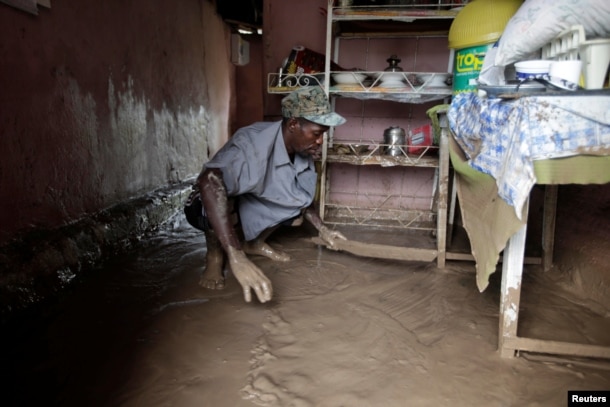 A man cleans out the water from his flooded house after Hurricane Matthew in Les Cayes, Haiti, October 5, 2016.