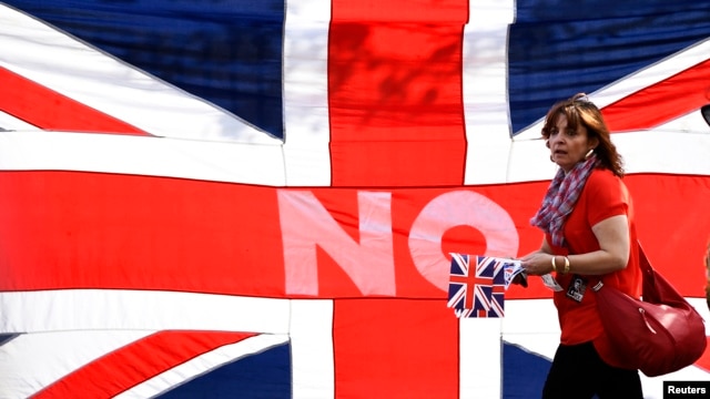 在苏格兰爱丁堡举行的支持联合王国大会上，有人在英国国旗旁走过。(2013年9月13日)
