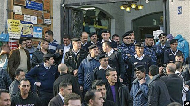Palestinian police officers block the entrance to the Al-Jazeera TV office, after protesters vandalized it, in the West Bank city of Ramallah, 24 Jan 2011