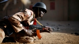 A Malian soldier takes cover behind a truck during exchanges of fire with jihadists in Gao, northern Mali, Sunday, Feb. 10, 2013.