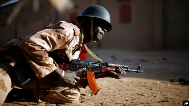 A Malian soldier takes cover behind a truck during exchanges of fire with jihadists in Gao, northern Mali, Sunday, Feb. 10, 2013.