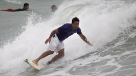 A surfer rides a wave whipped up by Tropical Storm Isaac at Haulover Beach Park in Miami Beach, Florida.