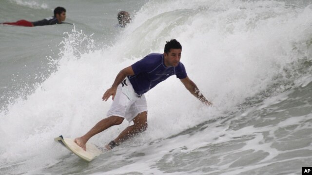 A surfer rides a wave whipped up by Tropical Storm Isaac at Haulover Beach Park in Miami Beach, Florida.