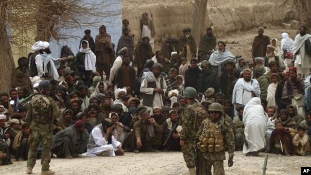 Afghan National Army soldiers keep watch as Afghans gather outside a U.S. base in Panjwai district Kandahar province, March 11, 2012. 