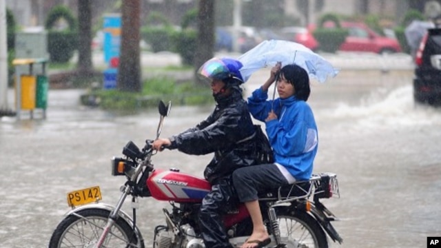 Man struggles to ride motorcycle carrying a woman during heavy rain brought by Typhoon Nesat in Qionghai, Hainan province September 29, 2011