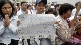 A Cambodian supporter holds a banner reading: "The court system must be respected by the public not for..." as she sits with other supporters of Mam Sonando, one of Cambodia’s most prominent human rights defenders, in front of Phnom Penh Municipal Court in Phnom Penh, Cambodia, Tuesday, Sept. 11, 2012. Some 300 supporters gathered for prayer for local radio station owner Sonando,  who has been held in pre-trial detention for almost two months for insurrection charge, during his court appearance. (AP Photo/Heng Sinith)