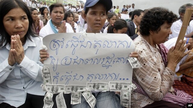 A Cambodian supporter holds a banner reading: "The court system must be respected by the public not for..." as she sits with other supporters of Mam Sonando, one of Cambodia’s most prominent human rights defenders, in front of Phnom Penh Municipal Court in Phnom Penh, Cambodia, Tuesday, Sept. 11, 2012. Some 300 supporters gathered for prayer for local radio station owner Sonando,  who has been held in pre-trial detention for almost two months for insurrection charge, during his court appearance. (AP Photo/Heng Sinith)