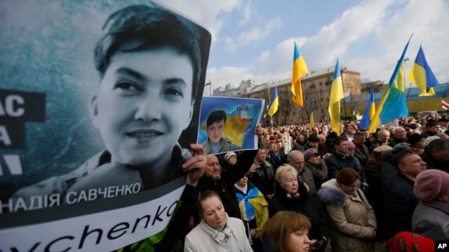 People hold posters depicting Ukrainian pilot Nadezhda Savchenko, during a interfaith prayer 