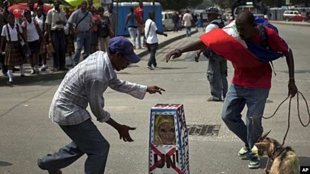 Demonstrators dance around a fake coffin with the UN initials on it during a protest against the United Nations, in Port-au-Prince, Haiti, October 19, 2011.