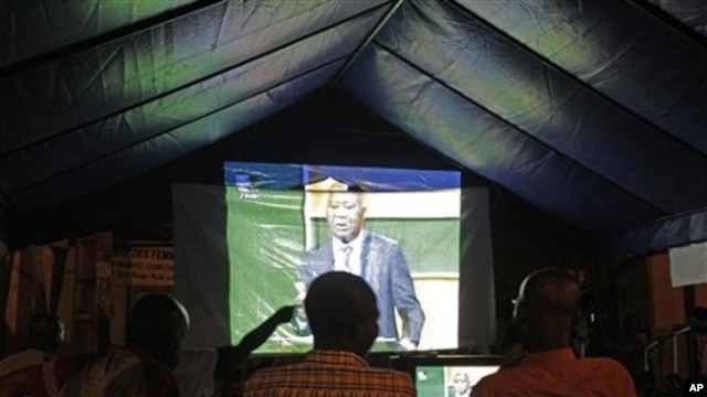 People watch on a big screen as Ivory Coast President Laurent Gbagbo talks during a live debate on national television with Ivory Coast opposition leader Alassane Ouattara in Abidjan, 25 Nov 2010