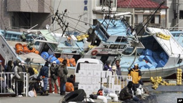Local residents wait for a ship to travel to a nearby island from the devastated city of Kesennuma, northeastern Japan, just one week after a massive earthquake and resulting tsunami, March 18, 2011