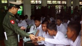 A Burma soldier (L) gives the national identity card to child soldiers who were recruited into the army before reaching the age of 18, during a ceremony where they were handed over to their parents and guardians in Rangoon, September 3, 2012.