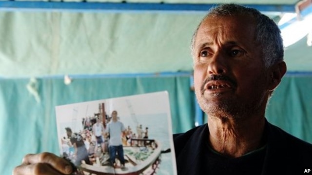 Tunisian man shows a photograph of his relative, who died while trying to reach Italy illegally, at coastal town Zarzis in southeastern Tunisia, February 18, 2011