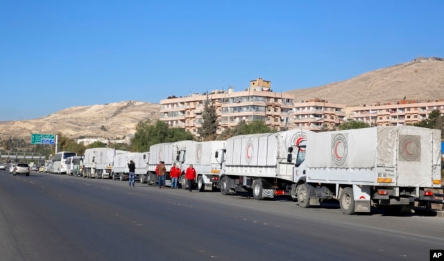 A convoy of humanitarian aid waits in front of the United Nations Relief and Works Agency (UNRWA) offices before making their way into the government besieged rebel-held towns of Madaya, al-Zabadani and al-Moadhamiya in the Damascus countryside, as part of a U.N.-sponsored aid operation, in Damascus, Syria, Feb. 17, 2016.