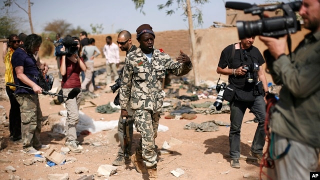 A Malian soldier gestures at journalists to leave the area of a French air strike. Image was taken during an official visit organized by the Malian army to the town of Konna, north of Mali's capital Bamako, January 26, 2013. 