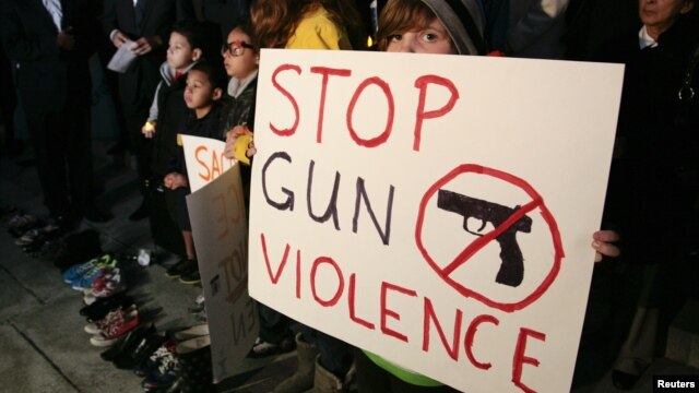Sophie Bell, 9, holds a sign during an interfaith candlelight prayer vigil to end gun violence in front of Los Angeles City Hall in Los Angeles, California, December 19, 2012.